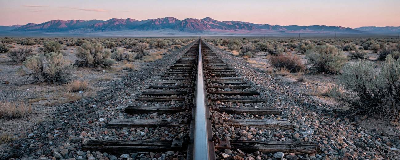 A single rail line through sagebrush basin at dawn.